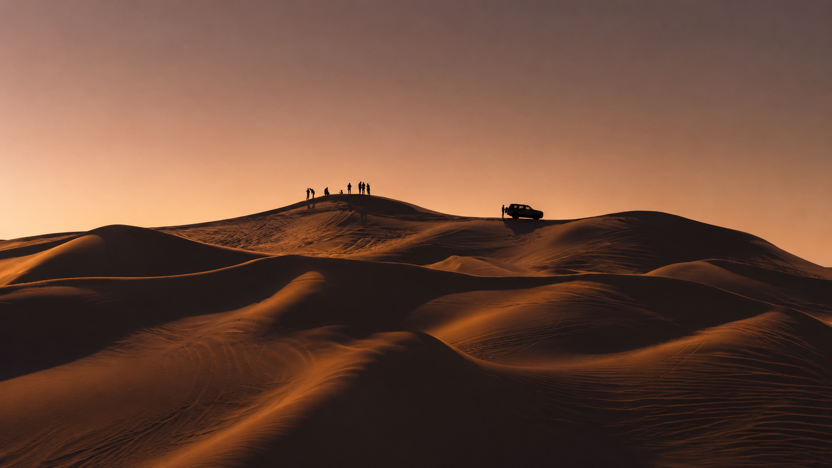 Desert landscape at sunset with people overlooking the dunes